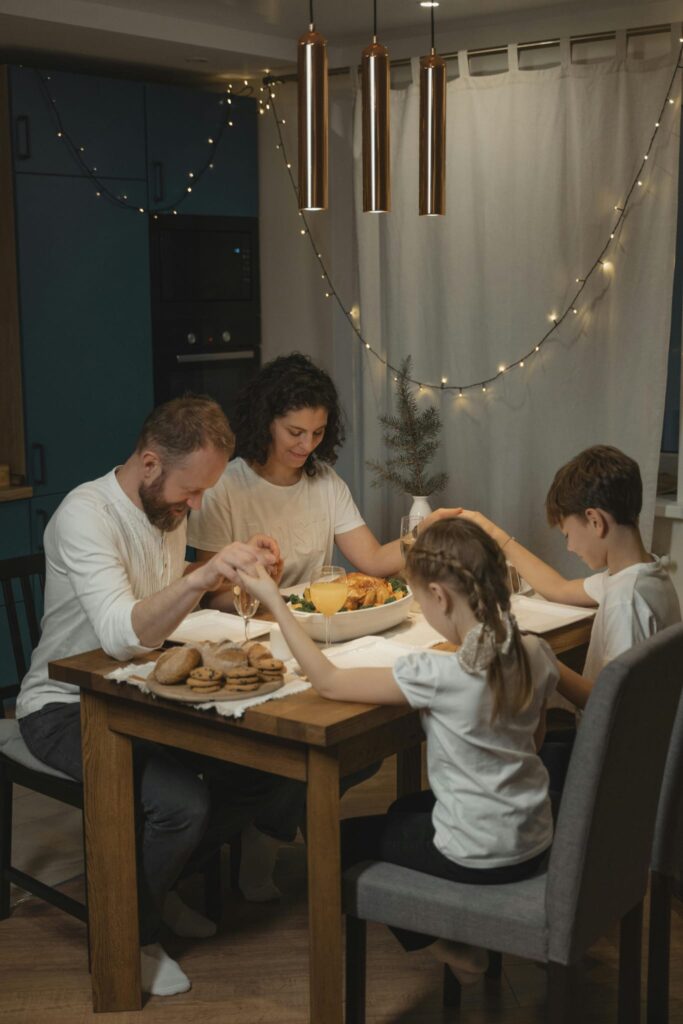 A family holding hands praying over dinner