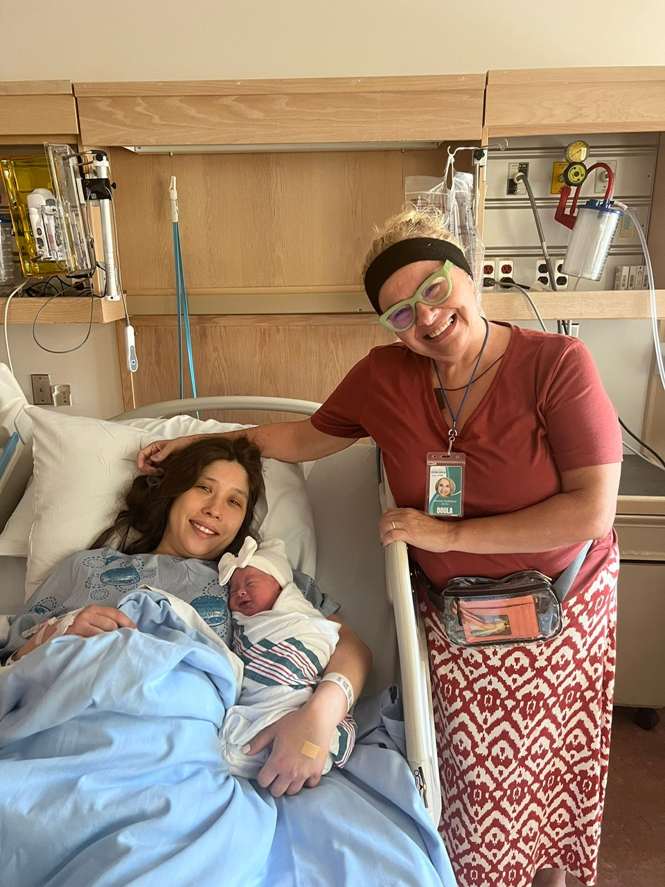 Happy momma with her new baby and her doula standing next to her